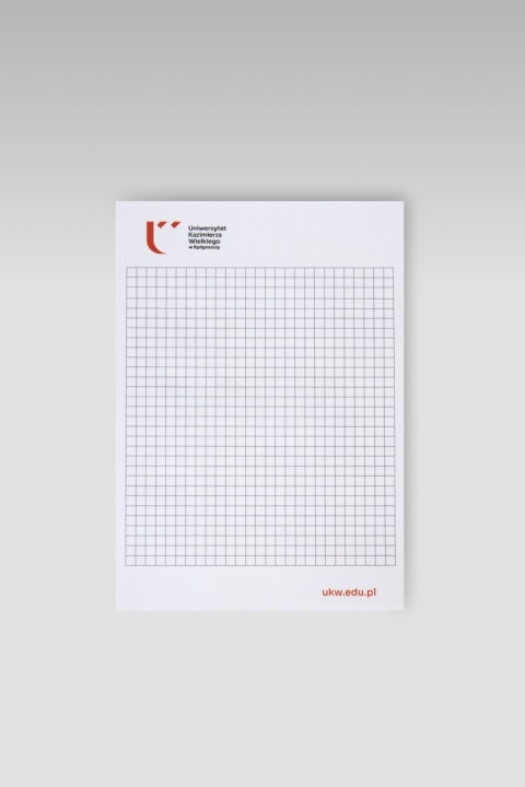 Notatnik A5 z białą stroną w kratkę, logo i nazwą Uniwersytetu Kazimierza Wielkiego w Bydgoszczy u góry oraz adresem ukw.edu.pl w prawym dolnym rogu.