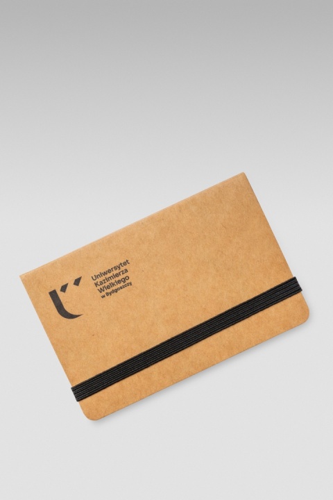Tylna okładka notesu z czarną gumką, metalowym elementem mocującym i oznaczeniem „Recycled paper”.