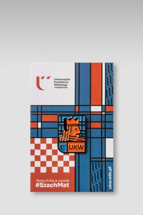 Pin UKW ze stylizowanym wizerunkiem króla, umieszczony na kolorowej karcie.